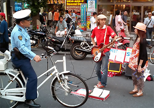 Tam, wśród śpiewaków, urzędnik władzy nadzoruje ulicę - policjant na rowerze